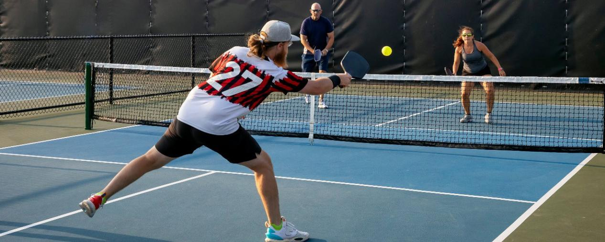 Pickleball players playing doubles match on blue court for beginner pickleball rules guide
